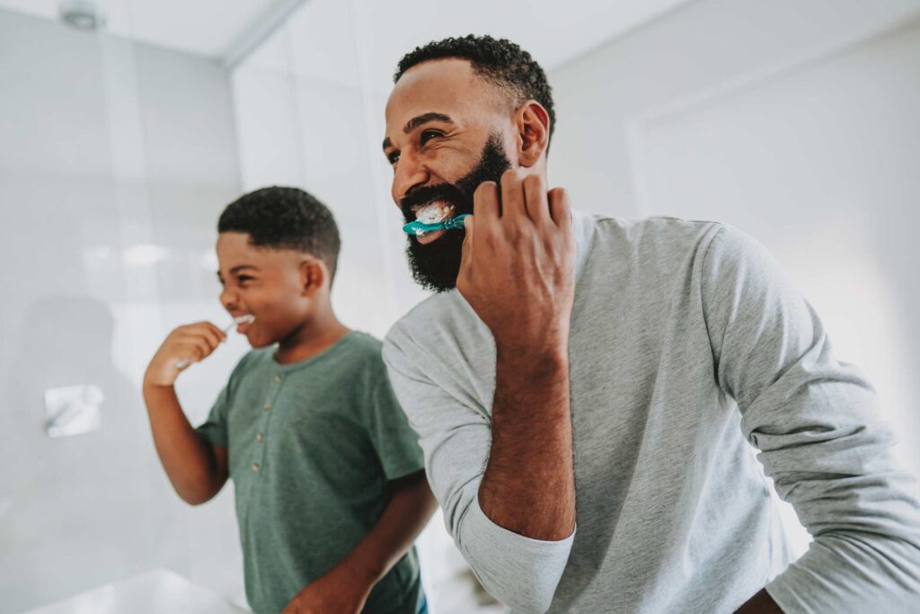 Adult and child brushing teeth together showing preventive dental care for all ages in Wheaton, IL.