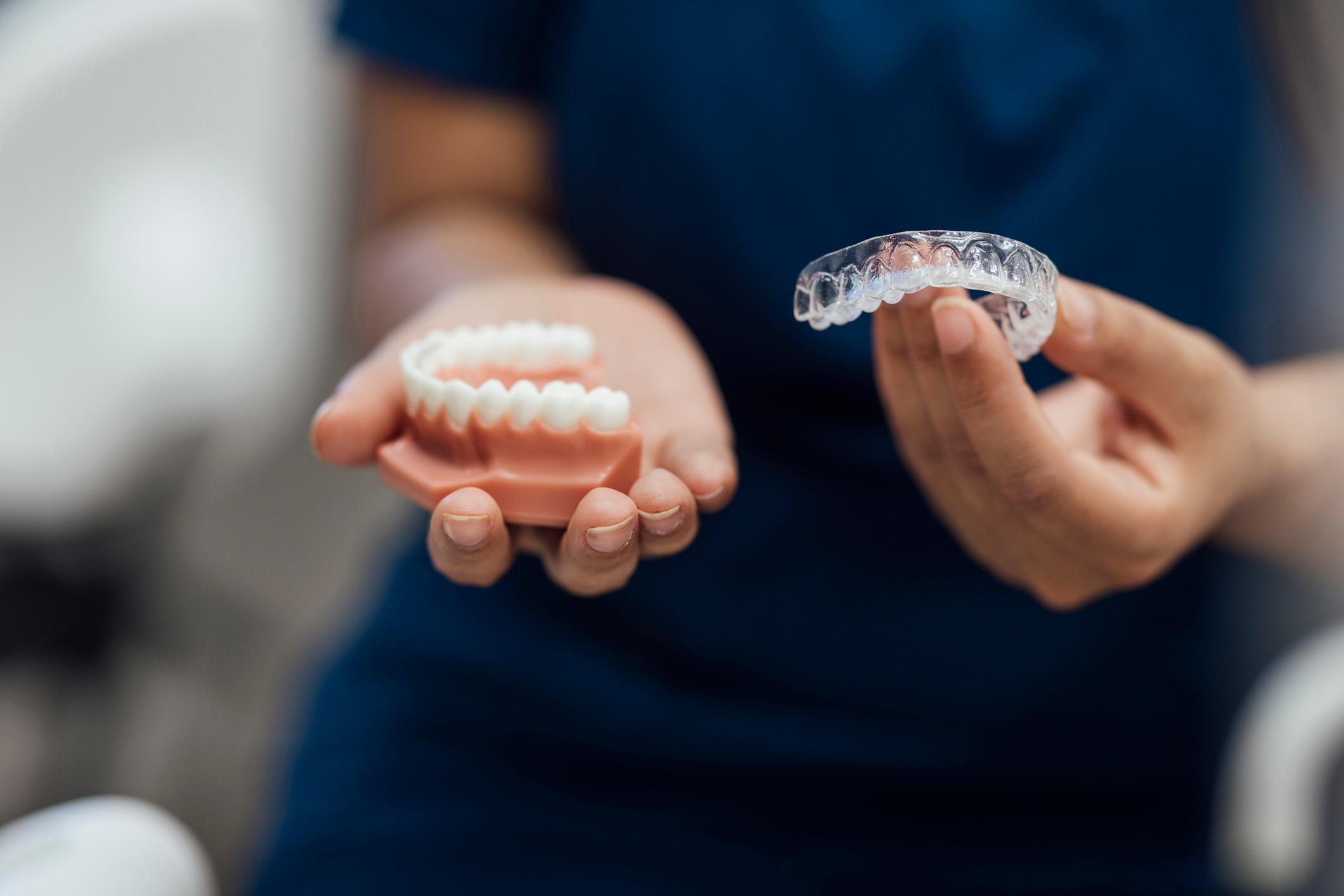 Patient holding Invisalign aligners during orthodontic treatment consultation in Wheaton, IL.